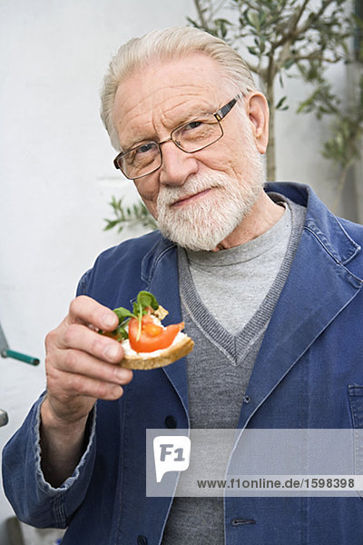 Ein älterer Mann hält einen Sandwich Tomaten Schweden.