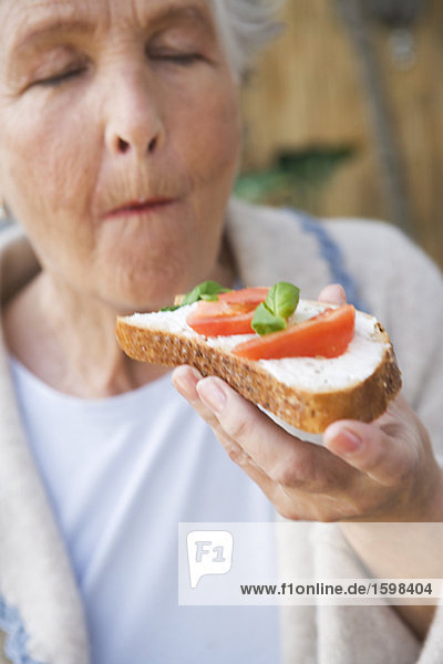 Frau Essen einen Sandwich mit Käse  Tomaten und Basilikum Schweden.