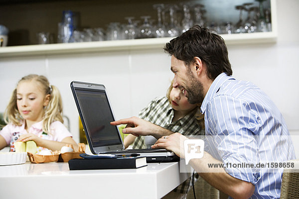 Father and children by a computer at home.