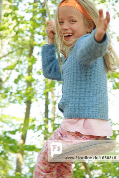Portrait of girl swinging on rope and laughing