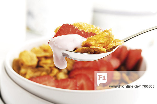Cornflakes und Erdbeeren auf Löffel Nahaufnahme Cornflakes und Erdbeeren auf Löffel, Nahaufnahme