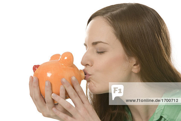 Junge Frau küsst Sparschwein  Porträt