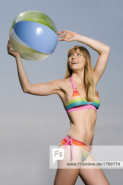 Junge Frau im Bikini spielt mit Ball