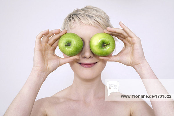 Junge Frau hält Äpfel über die Augen  Portrait