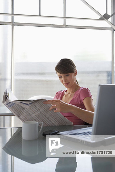 Woman at desk reading newspaper