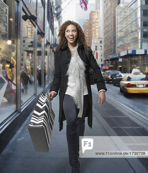 Woman carrying shopping bags down urban street