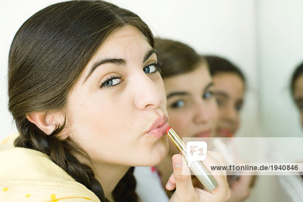 Young female friends putting on make-up mouth