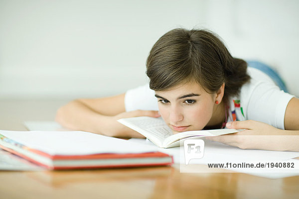 Teenagerin auf dem Boden liegend  Hausaufgaben machend