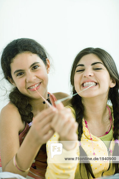 Zwei junge Freundinnen ziehen Kaugummi aus dem Mund  Portrait