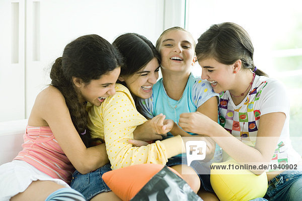 Four young female friends tickling each other and giggling