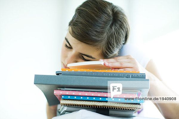 Teen girl resting head on stack of homework  eyes closed