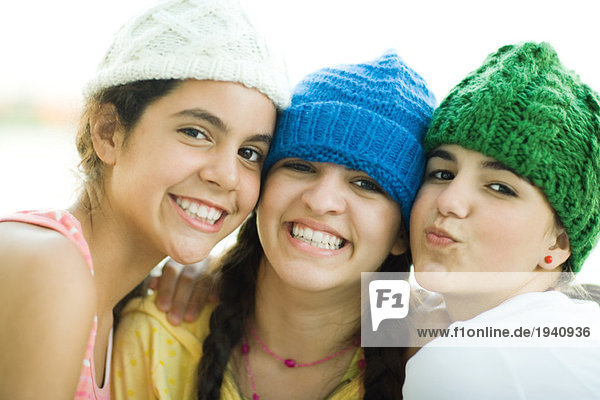 Young female friends wearing knit hats  smiling at camera