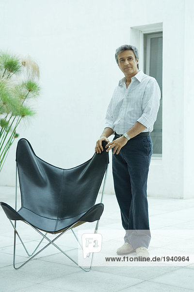 Erwachsener Mann steht neben dem Stuhl  Ganzkörperporträt