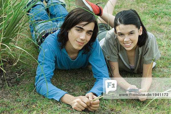Teen couple listening to MP3 player together  lying on grass