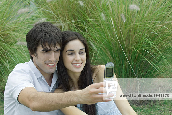 Young couple posing while man holds up cell phone to take photo