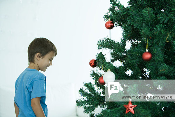 Junge steht am Weihnachtsbaum