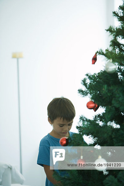 Junge steht am Weihnachtsbaum