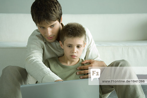 Junge und Vater benutzen gemeinsam einen Laptop