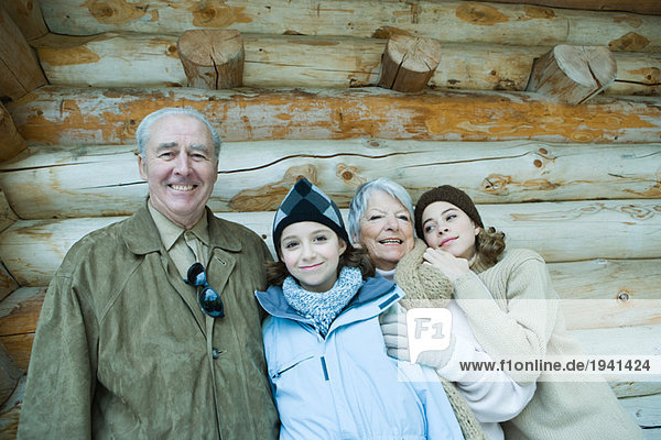 Seniorenpaar stehend mit Teenagern und Enkelinnen vor der Blockhütte  lächelnd  Portrait