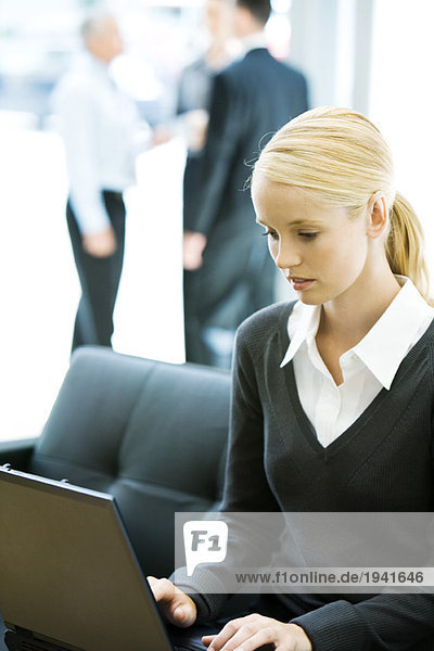 Young business woman using laptop computer  associates in background