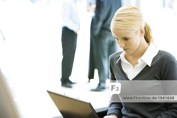 Young businesswoman using laptop computer  looking down  waist up