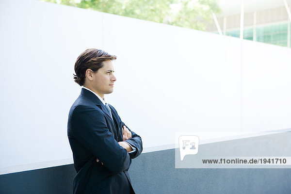 Young businessman standing with arms folded  looking away