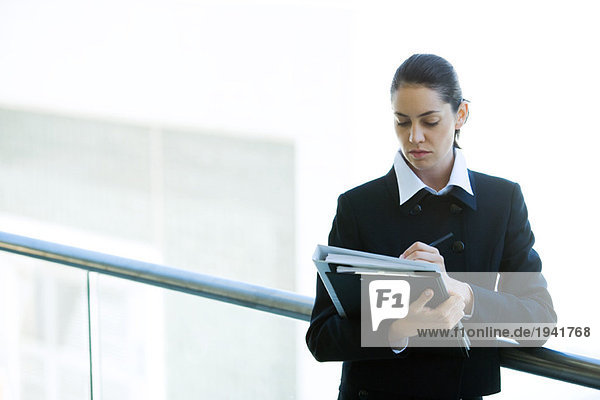 Junge Geschäftsfrau schaut auf Mappe  Schriftzug  Taille hoch