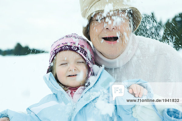 Großmutter und Enkelin im Schnee  beide lächelnd  Augen geschlossen