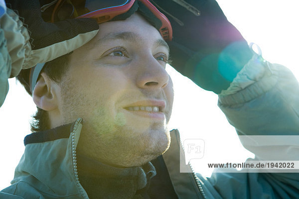 Young man taking off ski goggles  smiling