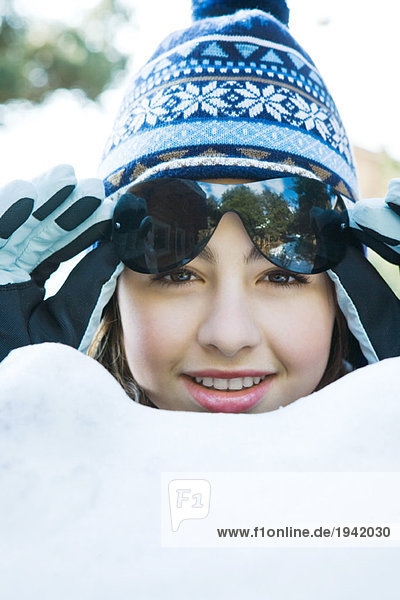 Teenagermädchen im Schnee  Winterkleidung tragend  Sonnenbrille hebend  Portrait