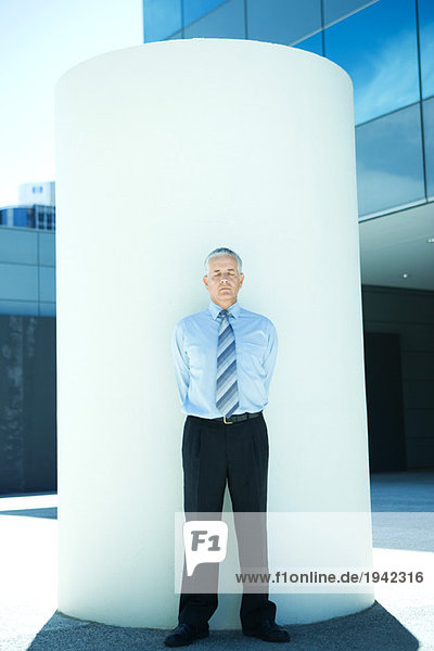 Businessman standing in front of cylinder  eyes closed  full length