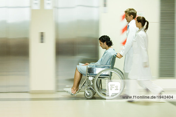 Krankenhauspersonal schiebt Mann im Rollstuhl  verschwommene Bewegung