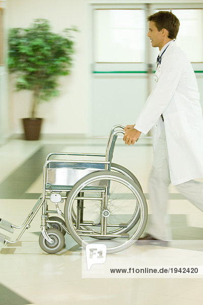 Männlicher Arzt schiebt leeren Rollstuhl  verschwommene Bewegung