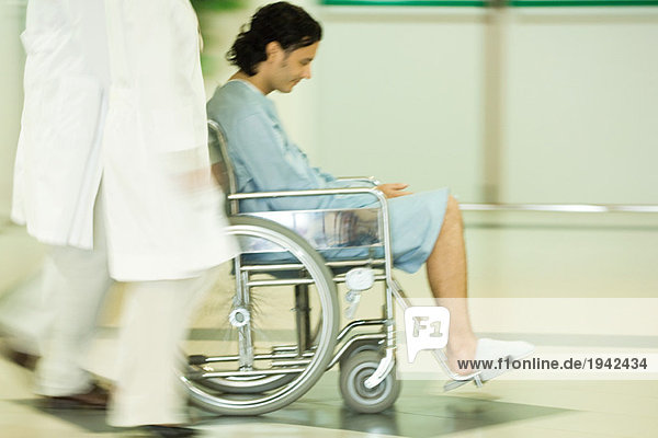 Medizinisches Personal schiebt Mann im Rollstuhl  verschwommene Bewegung