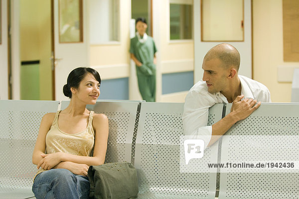 Zwei Erwachsene sitzen im Wartezimmer des Krankenhauses und plaudern.