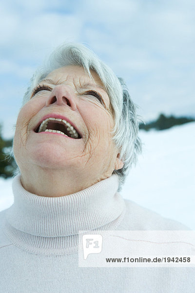 Seniorin lacht mit Kopf zurück in verschneiter Landschaft  Portrait