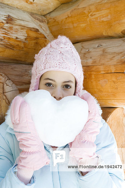 Preteen girl holding up heart made of snow  portrait