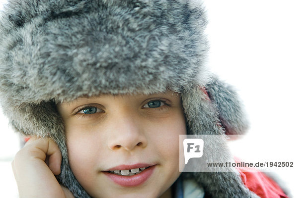 Boy wearing fur hat  smiling at camera  close-up