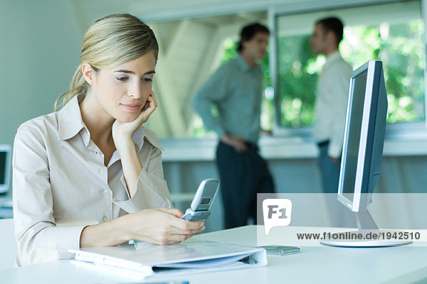 Young businesswoman in office  using cell phone  looking down
