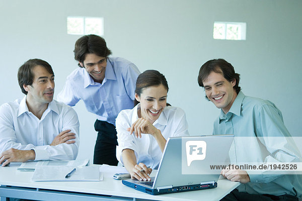 Four business associates using laptop computer  smiling