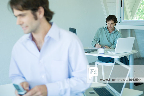 Businessman in office  writing  full length  associate in foreground