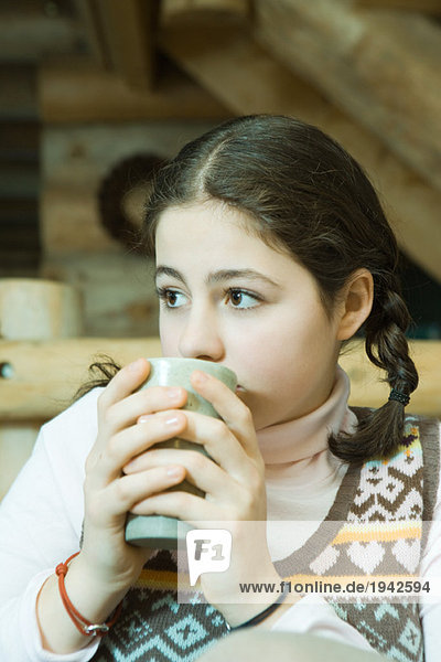 Teenagermädchen trinkt heißes Getränk  schaut weg