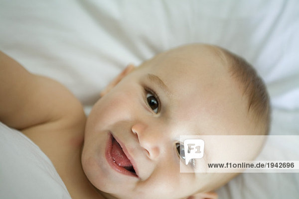 Baby lying on back  smiling at camera  head and shoulders