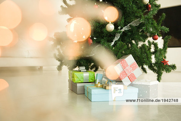 Weihnachtsgeschenke unter dem Weihnachtsbaum gestapelt  Blick durch die Weihnachtsbeleuchtung  selektive Fokussierung