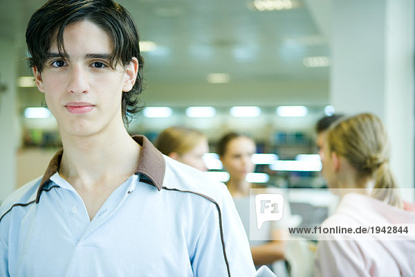 Male student smiling at camera  portrait  peers in background