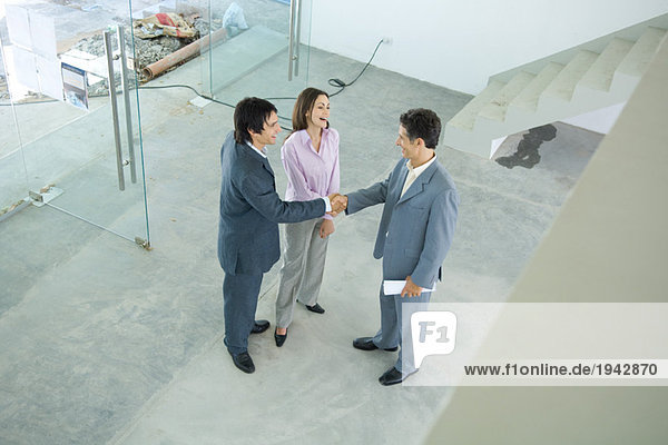Male real estate agent standing in home interior with young couple  full length  high angle view