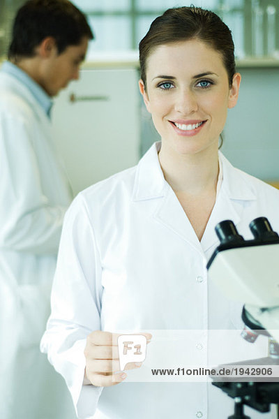 Young woman in laboratory  holding microscope slide  portrait