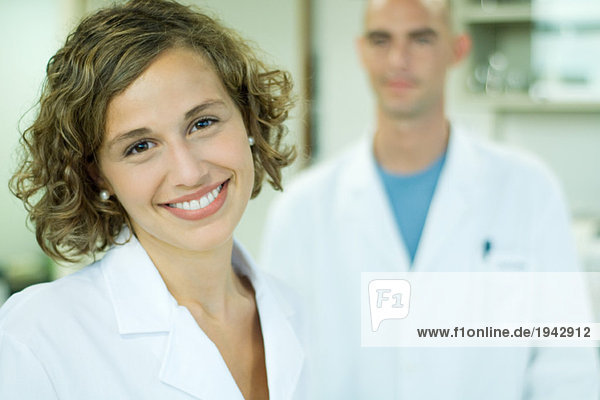 Female doctor smiling  male colleague in background  portrait