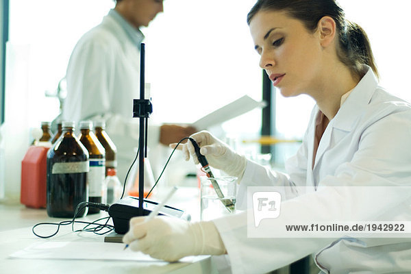 Young woman working in scientific laboratory  taking notes