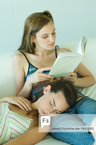 Junge Frau auf Couch Lesebuch  Freundin ruht mit geschlossenen Augen auf dem Schoß